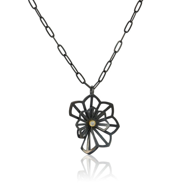 pendant in Karin Jacobson's Origami flower style made in oxidized sterling silver with center diamond set in 18k gold