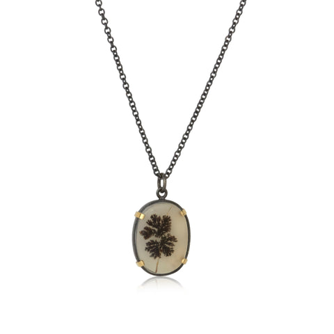 shows a pendant with an oval dendritic agate set in 18k gold and oxidized sterling silver on an oxidized sterling cable chain