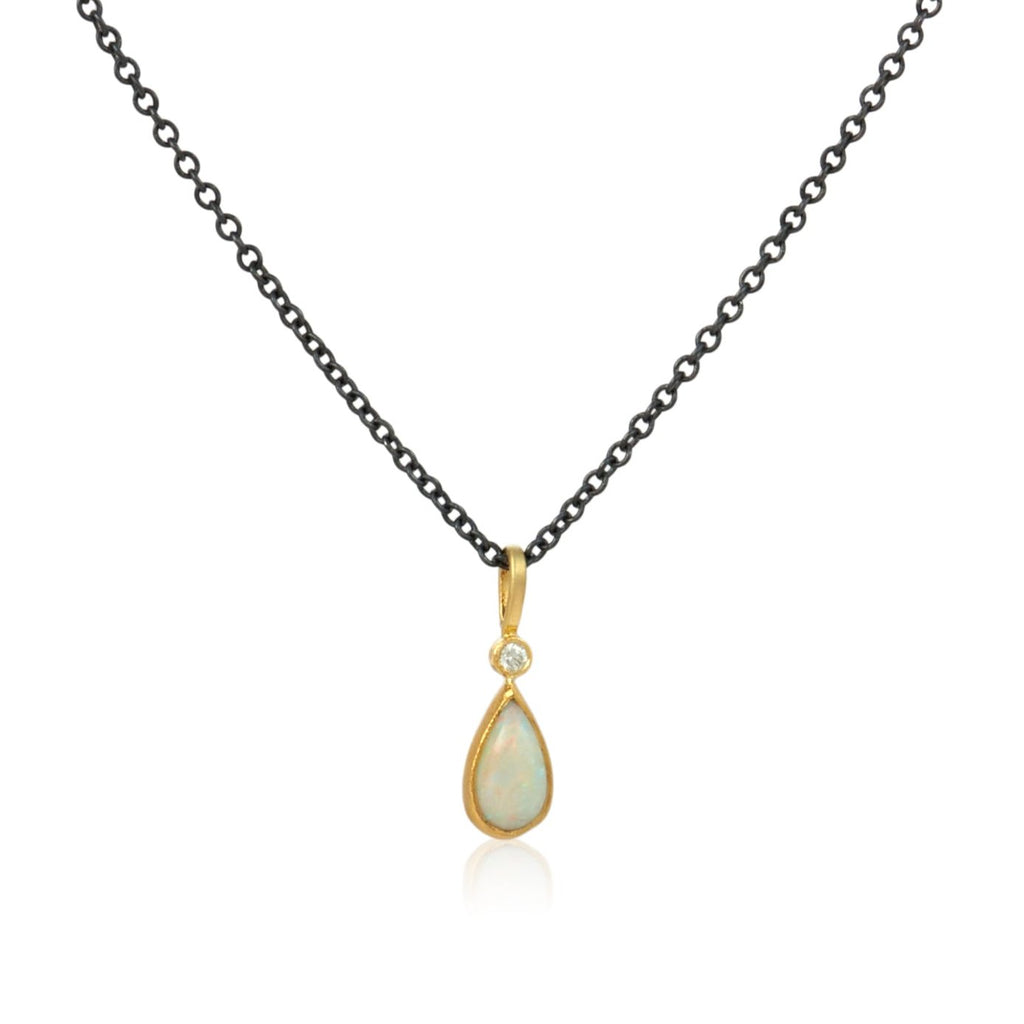 shows a milky pear shaped opal set in gold with a diamond at the top on a black cable chain